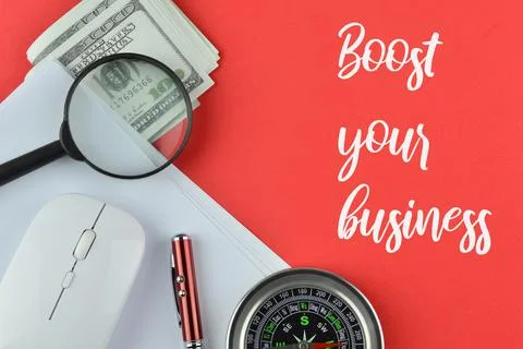 Office tools over red background written with BOOST YOUR BUSINESS. Stock Photos