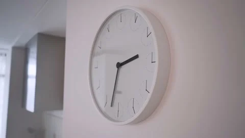 The office white clock hanging on white the wall is ticking, showing two hours Stock Footage 161890309