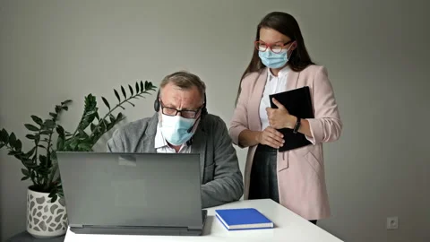 Office work during the covid-19 epidemic. Young employee helps a manager solve Stock Footage 138426076