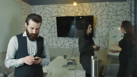 Office work. A man with a beard holding a mobile phone in his hands and working Stock Footage 149514334