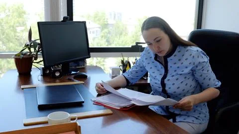 Office worker analyzing paperwork and using computer, focusing on business Foto stock
