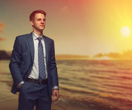 Office worker on the beach during sunset. Stock Photos