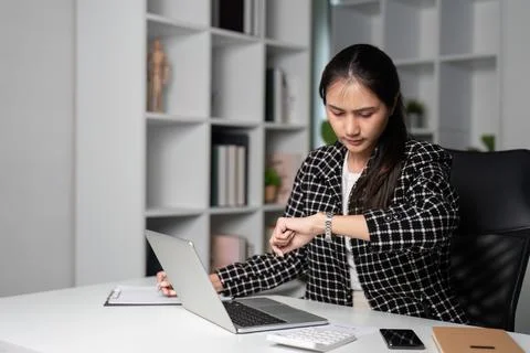 Office Worker Checking Time While Working Late in Modern Office Environment Stock Photos