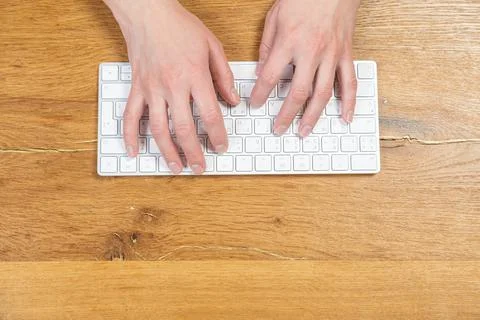 Office worker checks email while sitting at a wooden table. Stock Photos