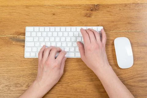 Office worker checks email while sitting at a wooden table. Stock Photos