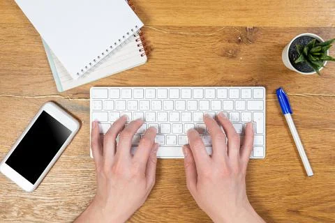 Office worker checks email while sitting at a wooden table. Stock Photos