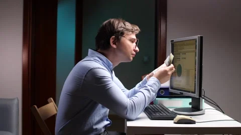 Office worker comparing banknotes with computer screen information Stock Footage 309242422