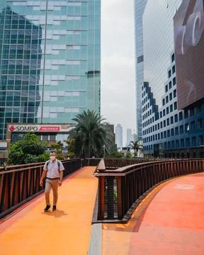 An office worker is crossing using a pedestrian bridge during the day Stock Photos