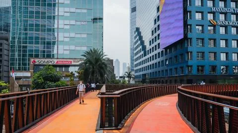 An office worker is crossing using a pedestrian bridge during the day Stock Photos
