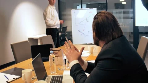 An office worker delivers a presentation on a whiteboard, while another at a Stock Footage 270320841
