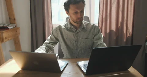Office worker does not have time to do all the tasks. Man sits at two laptops Stock-Footage 203729597