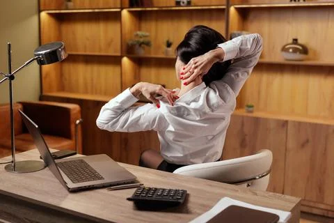 Office worker doing seated neck stretch for posture and pain relief at desk Stock Photos