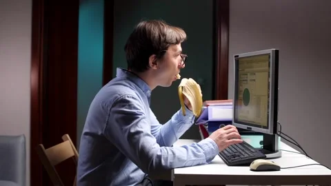 Office worker eating banana while working on computer at night Stock Footage 309241651