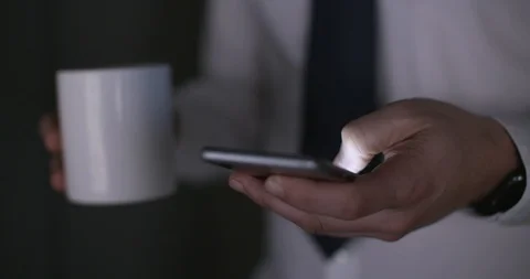 Office worker at the end of the day typing a message on phone with coffee Stock Footage 89917412