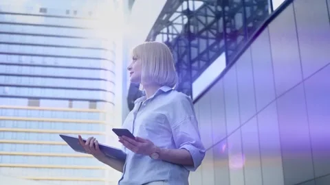 Office worker with folder and smartphone standing outdoors waiting for colleague Stock Footage 169033596