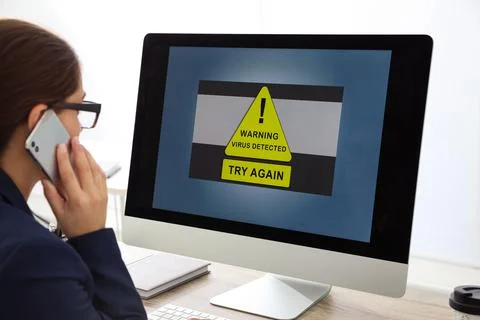 Office worker in front of computer with warning about virus attack on screen Stock Photos