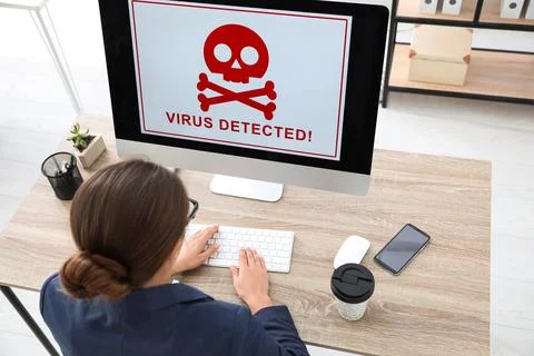 Office worker in front of computer with warning about virus attack on screen Stock Photos