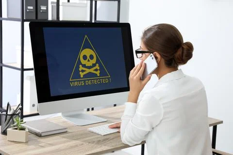 Office worker in front of computer with warning about virus attack on screen Stock Photos