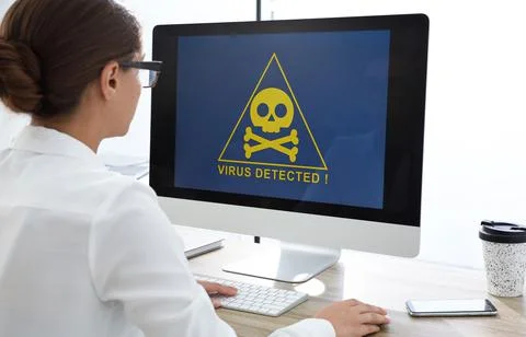 Office worker in front of computer with warning about virus attack on screen Stock Photos