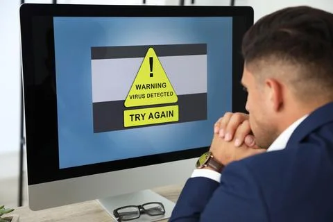 Office worker in front of computer with warning about virus attack on screen Stock Photos