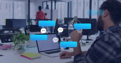 Office worker gesturing at chat bubbles after laptop alert, colleague scribbling Stock Footage 311584870