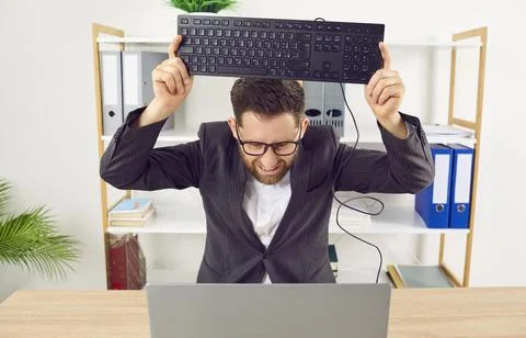 Office worker gets angry because of computer problem and wants to smash keyboard Stock Photos