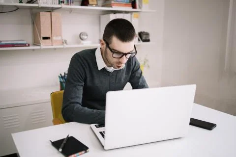 Office worker with glasses using laptop on desk Stock Photos