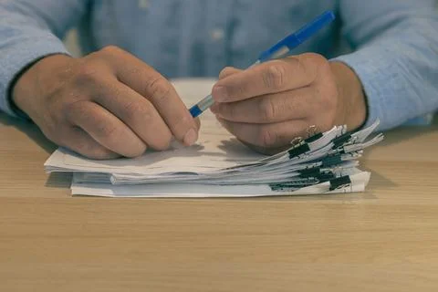 Office worker hands holding pen over stacked documents Stock Photos