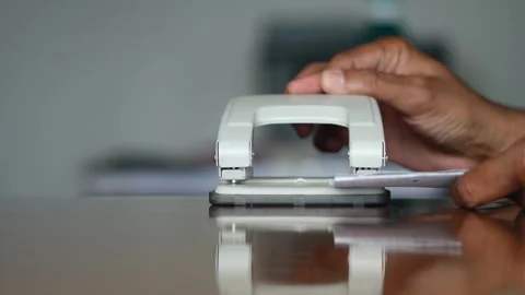 Office worker hands punching holes in paper documents Stock Footage 345549979