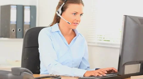Office worker with a headset typing on her computer Видео 7763312