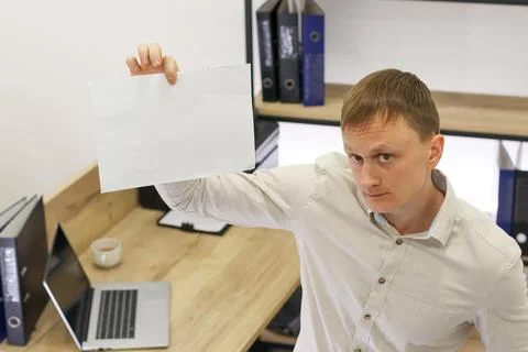 Office worker holding aloft empty white paper with focused look Stock Photos