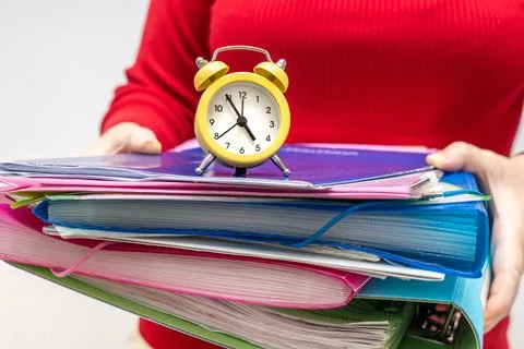 Office worker holding a pile of documents with an alarm clock, Concept, dea.. Foto stock