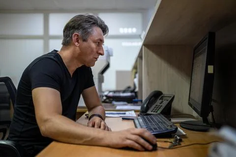 Office worker looking intently at computer monitor while using a mouse at h.. Stock Photos