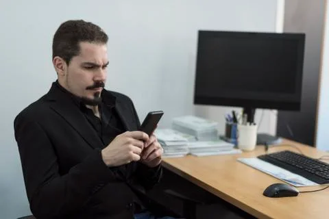 Office worker looking smartphone in workplace Stock Photos