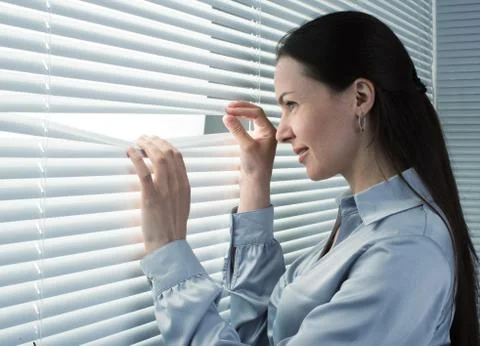 Office worker looking through window blinds Stock Photos