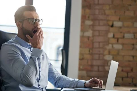 Office worker looking tired while using his laptop Stock Photos