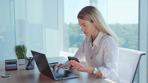 An office worker makes a calculation, a financial report, uses phone and laptop. Stock Footage 205445988