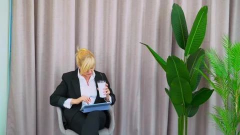 Office worker multitasks during coffee break, holding cup and working tablet Video stock 301525509