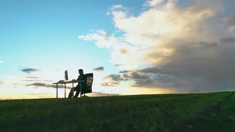 An office worker or freelancer sits alone in a field at sunset Stock Footage 164225664