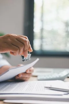 Office worker organizing paperwork with binder clips on desk, showing docum.. Stock Photos