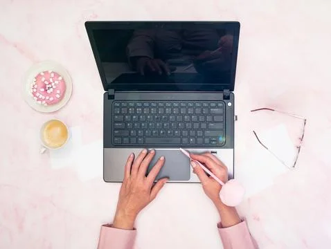 Office worker in a pink shirt sits at a laptop, top view,next to a cup of coffee Stock Photos