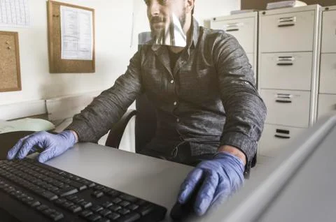 Office worker with plastic protective screen working on computer Stock Photos