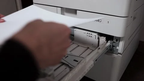Office worker putting a stack of paper A3 into the printer tray Stock Footage 294976229
