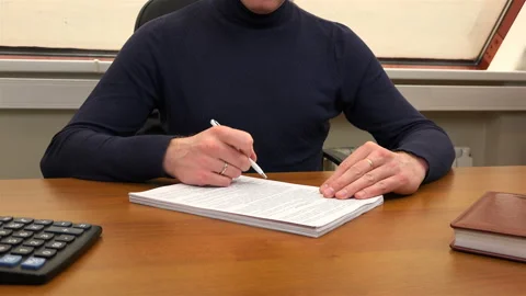 An office worker re-reads a document at his desk Stock Footage 100088706