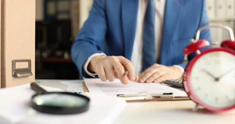 Office worker reads documents at table confirming recorded sum Stock Footage 318731377
