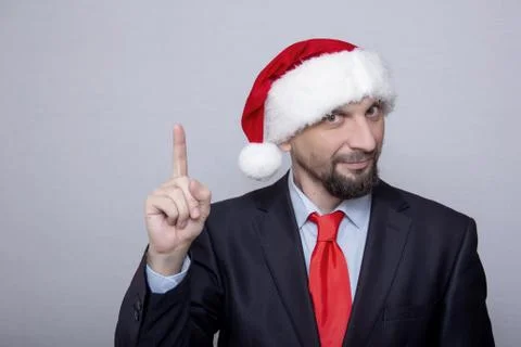 Office worker in Santa's hat points with his hand, a place for text 스톡 사진