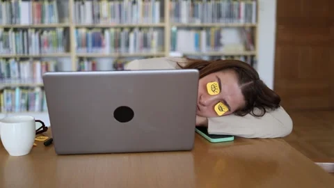 Office worker secretly naps behind laptop with funny sticky note eyes Stock-Footage 342178456