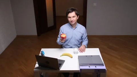 Office worker showing an apple during work break with healthy food on desk Stock Footage 306549564