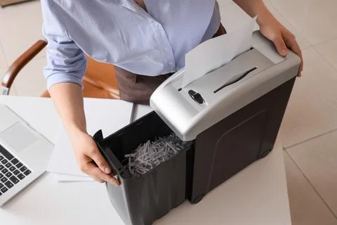 Office worker shredding confidential documents for data protection and inform Stock Photos