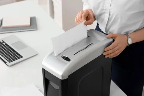 Office worker shredding confidential documents for data protection and inform Stock Photos
